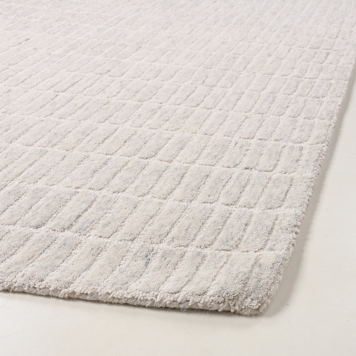 Light wool rug with raised rectangular patterns.