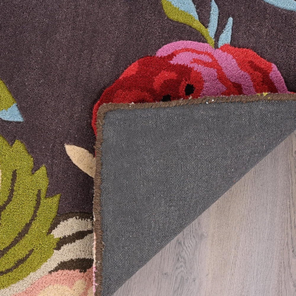 Close-up floral rug, dark brown with folded corner, grey backing.