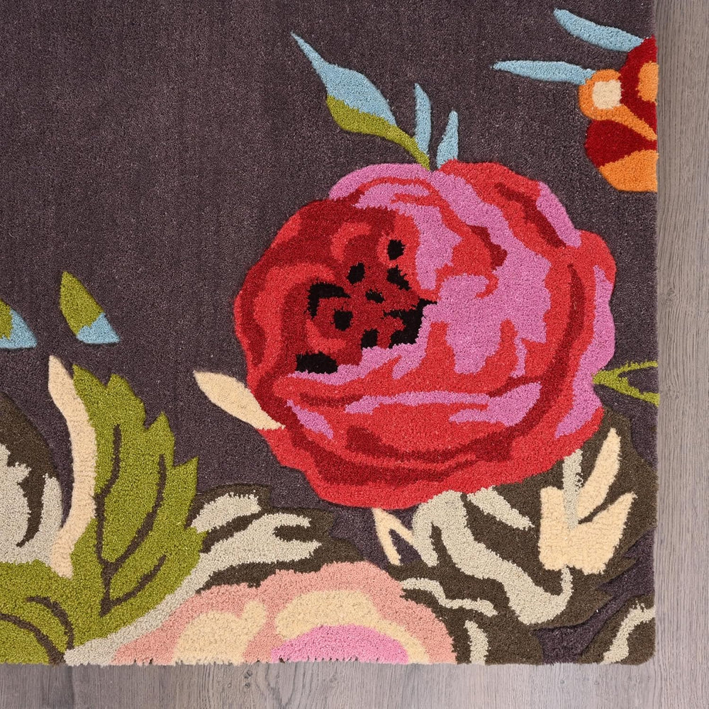 Close-up dark grey rug with red-pink floral design.