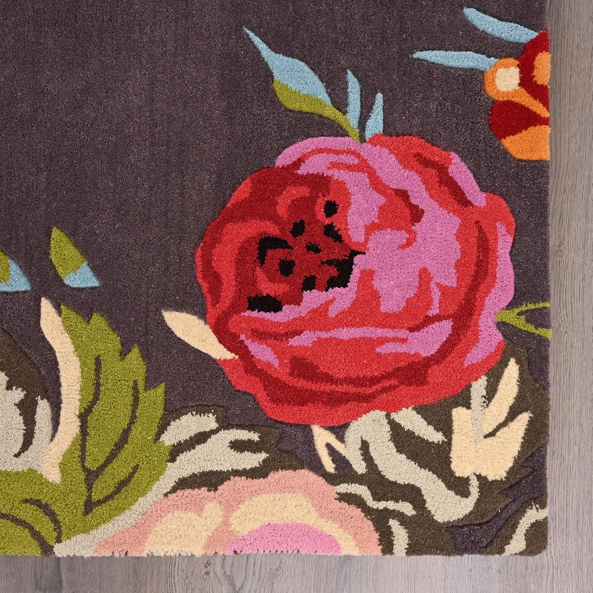 Close-up dark grey rug with red-pink floral design.