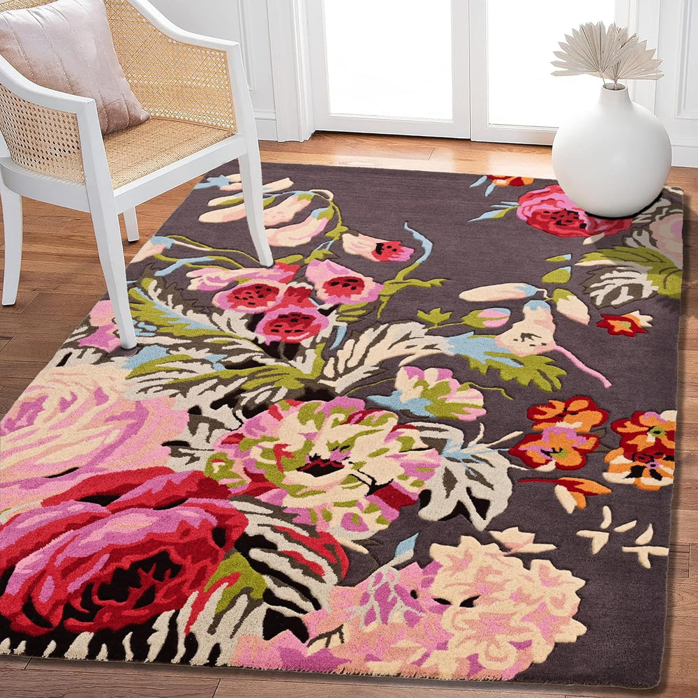 Floral rug with pink, red flowers, dark background, chair, vase.