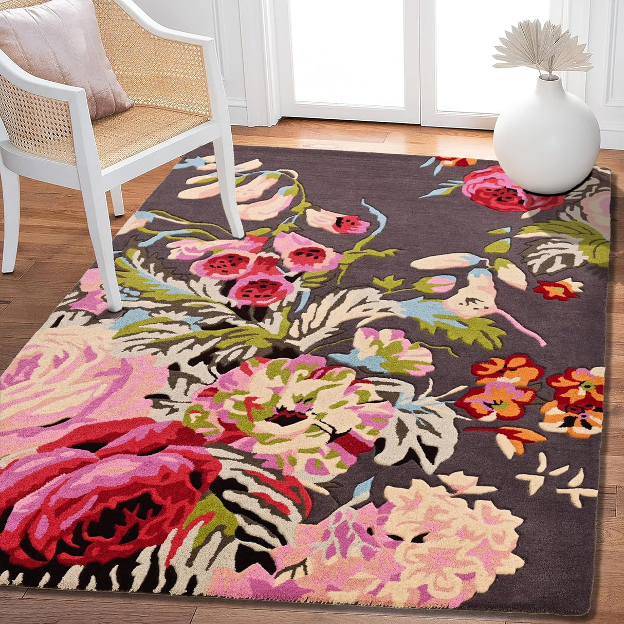 Floral rug with pink, red flowers, dark background, chair, vase.