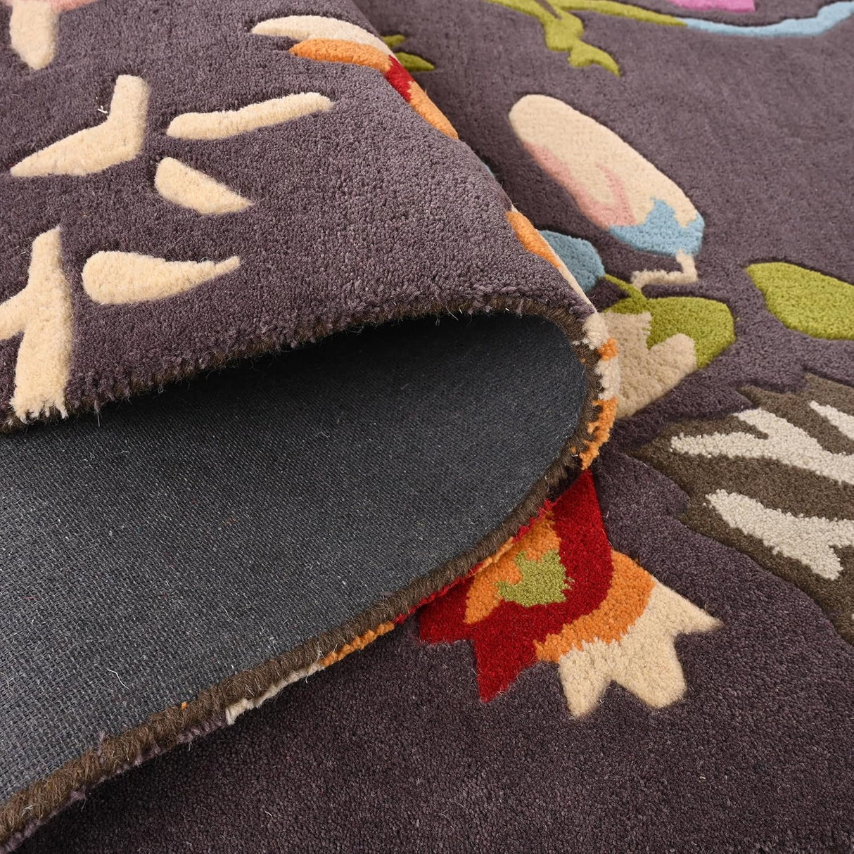 Close-up floral rug, dark base, colorful pattern, folded corner.