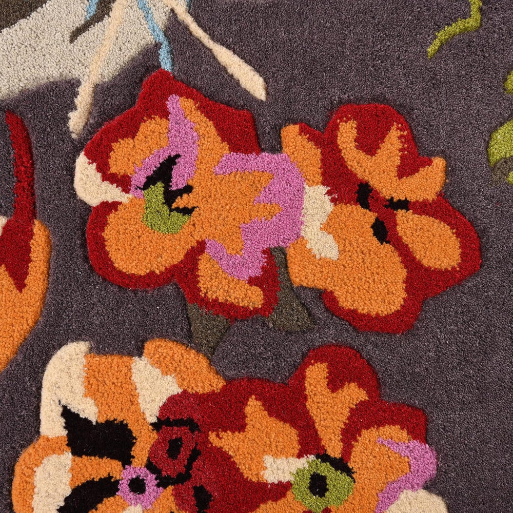 Close-up floral rug, red-orange flowers on dark grey.