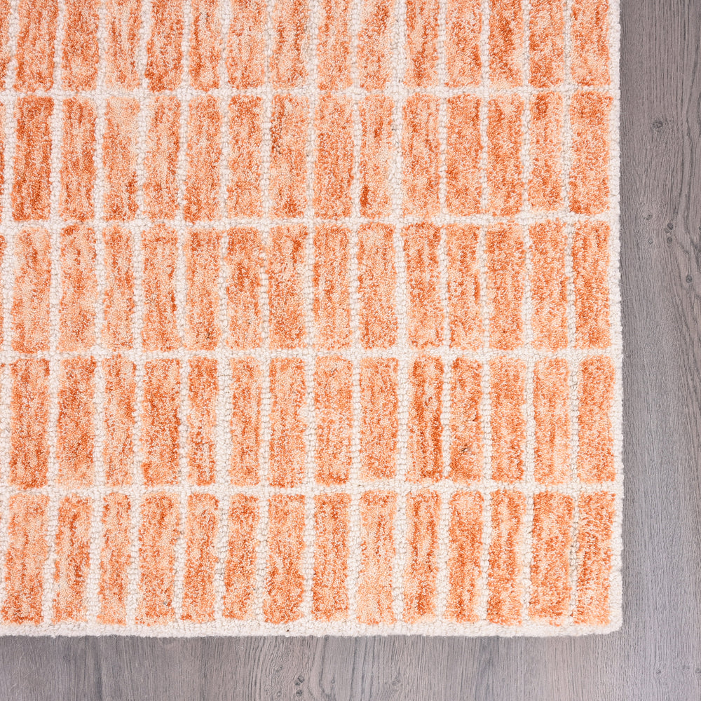 Close-up peach rug with raised block pattern on light background.