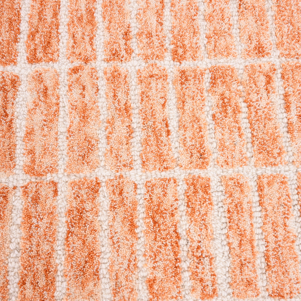 Close-up rug with orange-off-white block pattern.