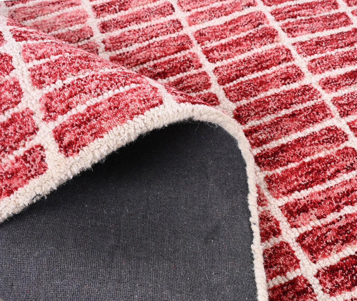 Close-up red-white rug, partially rolled, gray underside.